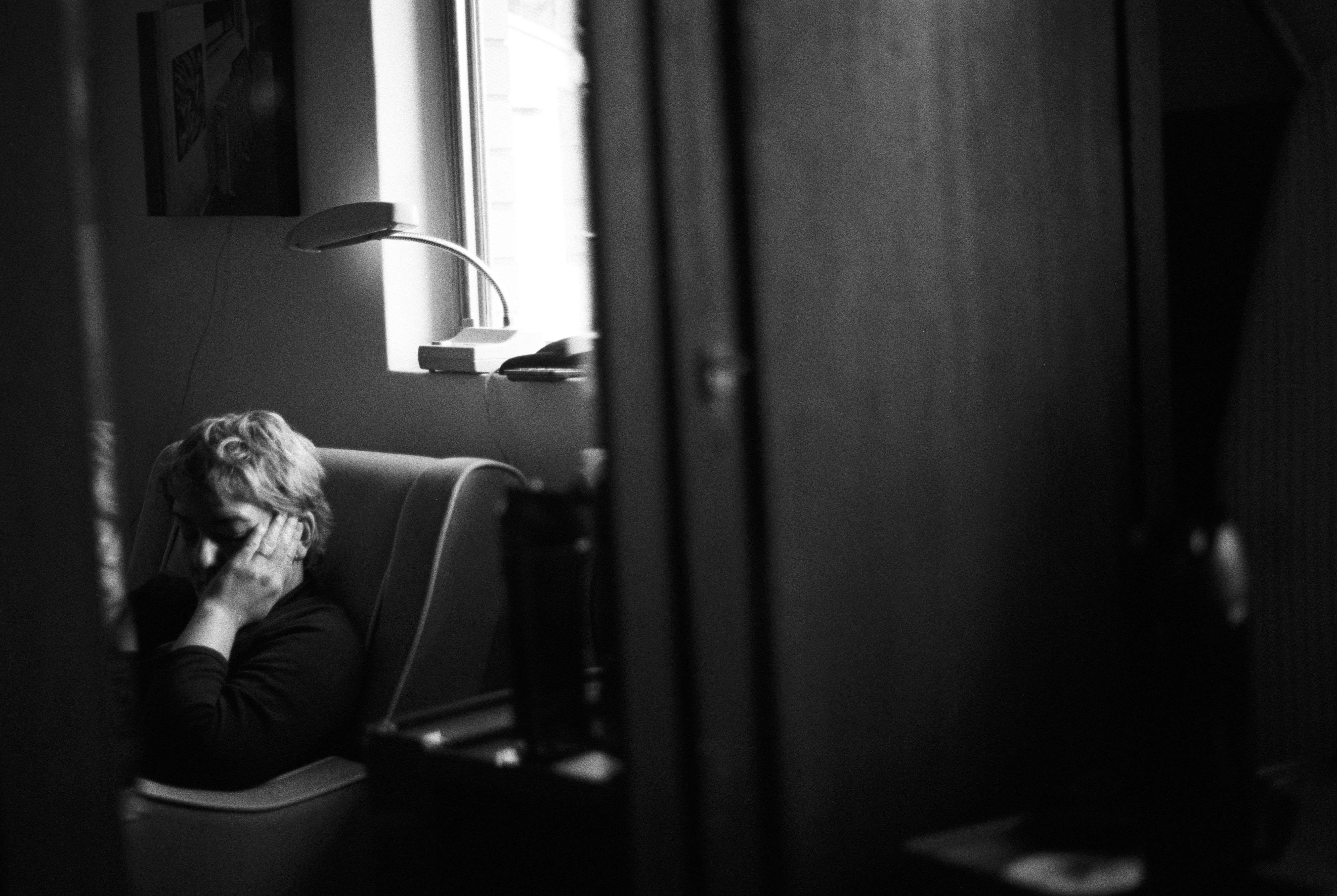 A black and white photo of someone reading in a chair photographed via reflection