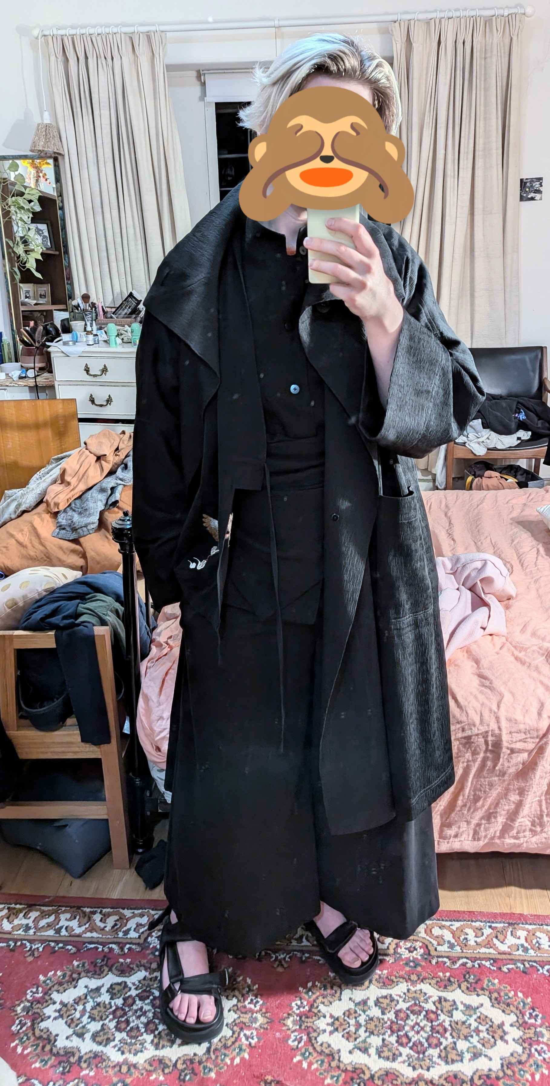 an androgynous person wearing multiple layers of draped black clothing